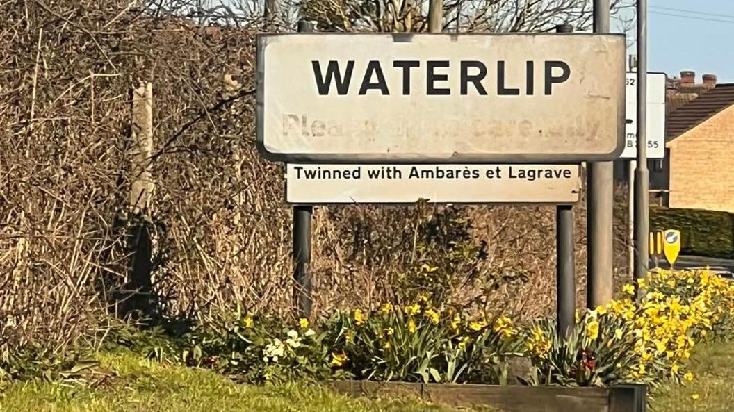 A sign with the word "Waterlip" on it with a sign underneath is saying "twinned with Ambares et Lagrave"