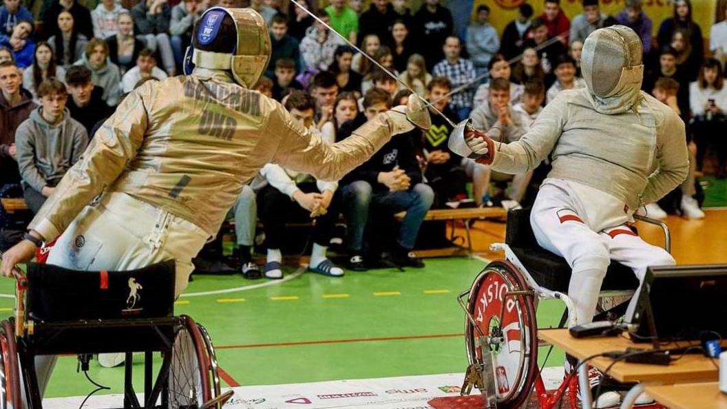 Andrii Demchuk lunges while watched by a crowd of schoolchildren as he participates in Para-fencing