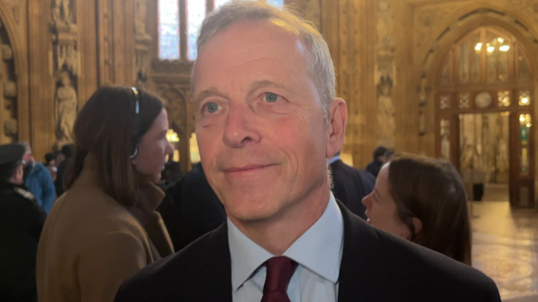 Labour MP for Reading Matt Rodda smiling at the camera is wearing a black jacket, blue shirt and red tie.