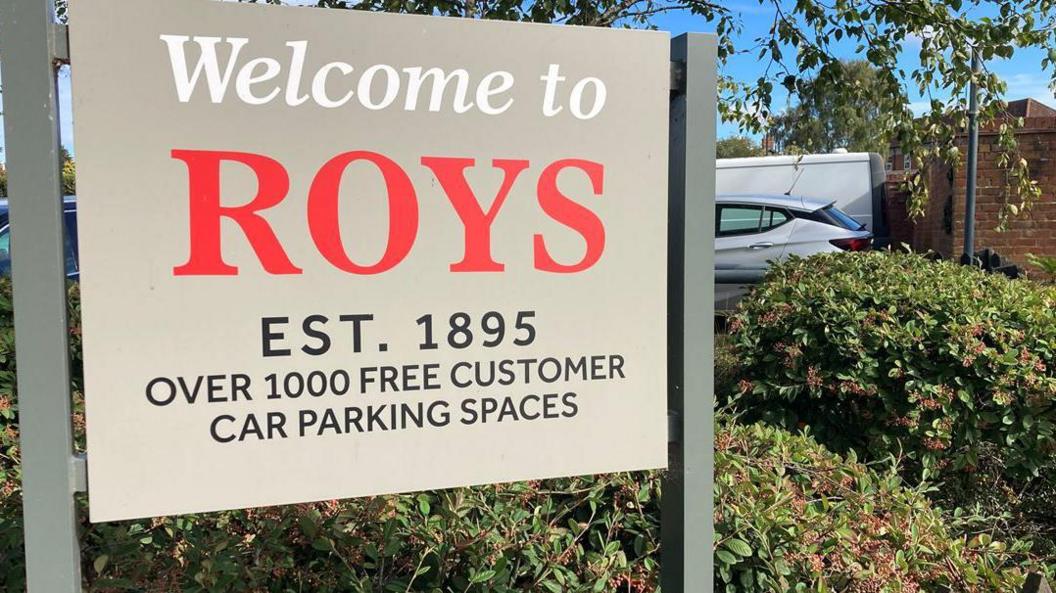 Roys car park sign in grey, red and white branding.