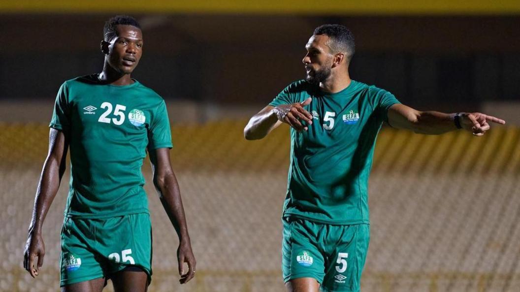 Juma Bah and Steven Caulker are seen wearing a green Sierra Leone training kit as Caulker points and instructs Bah.