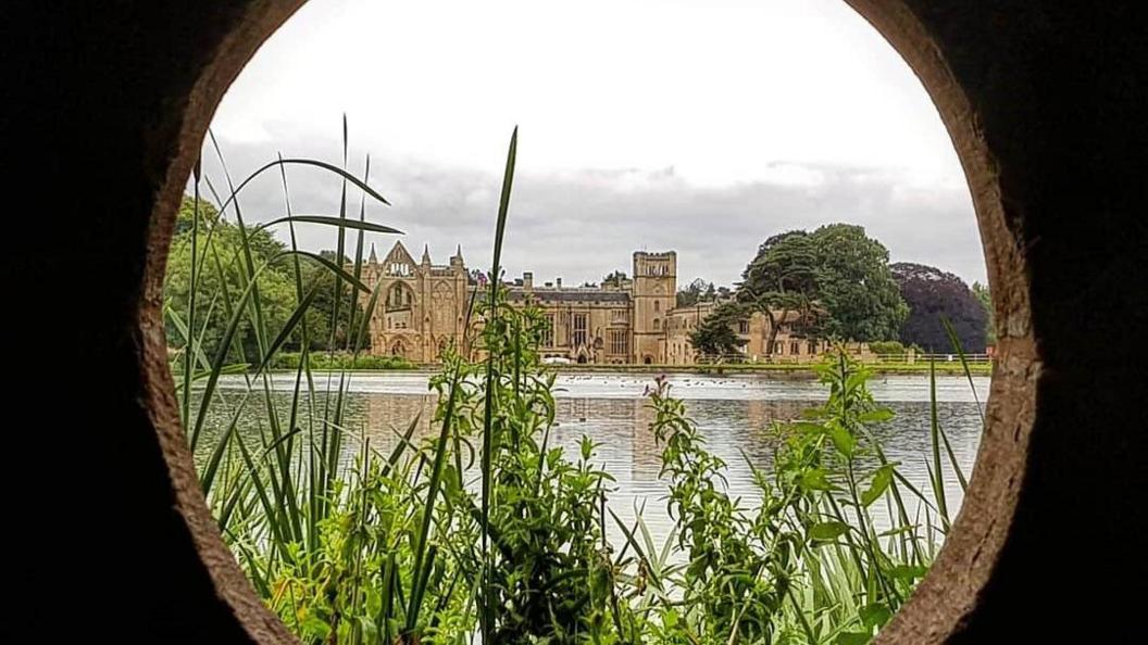 Newstead Abbey seen across a body of water through a circular hole