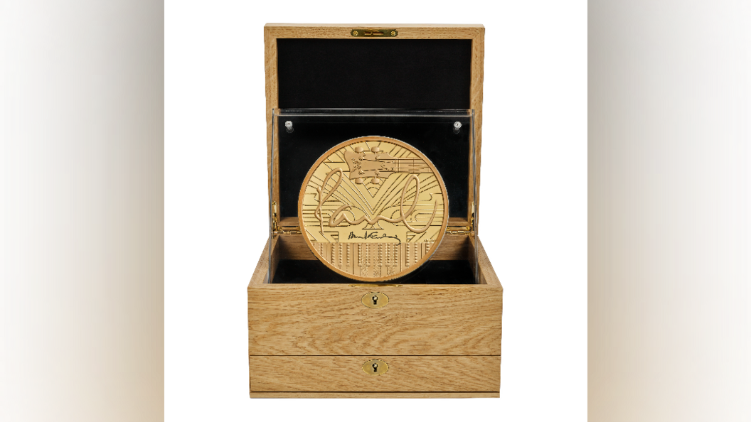 A gold coin with Paul McCartney's signature on, guitar and piano. Presented in a wooden box