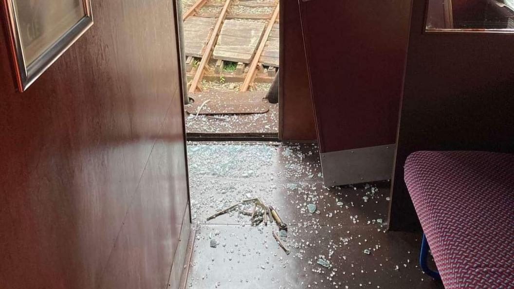 The inside of a train carriage with broken glass on the floor