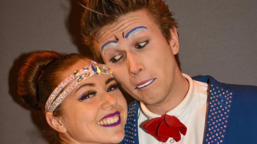 Mr and Mrs Herrin rest their heads on each other and smile at the camera. They both wear circus costumes.