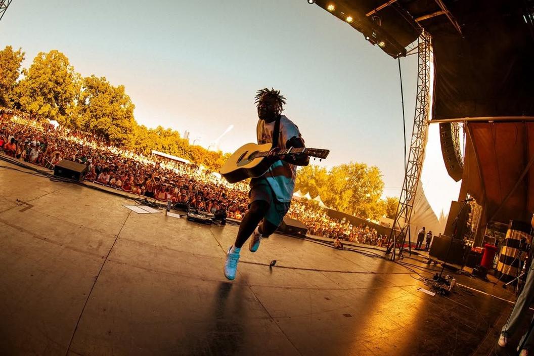 Myles Smith jumps in the air while playing to a huge crowd at an outdoor festival