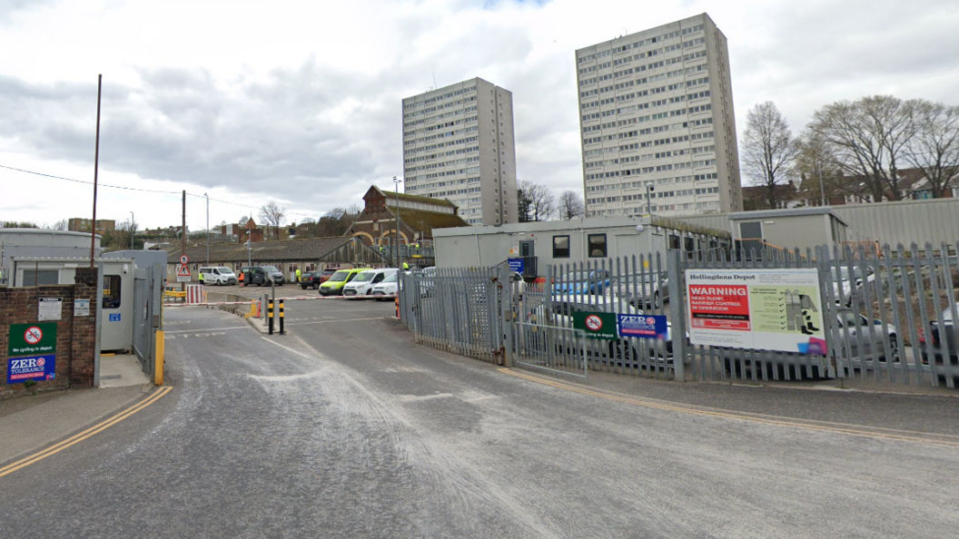 Waste depot in Hollingdean - a gate with signs and two tower blocks in the background