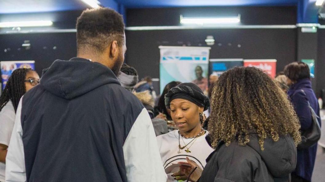 Natalie Scarlett speaking to people at an exhibition