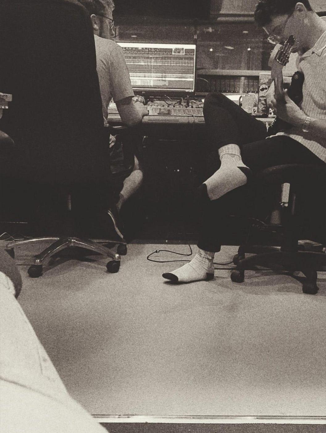 Dau gerddor tu ôl i ddesg sain mewn stiwdio recordio