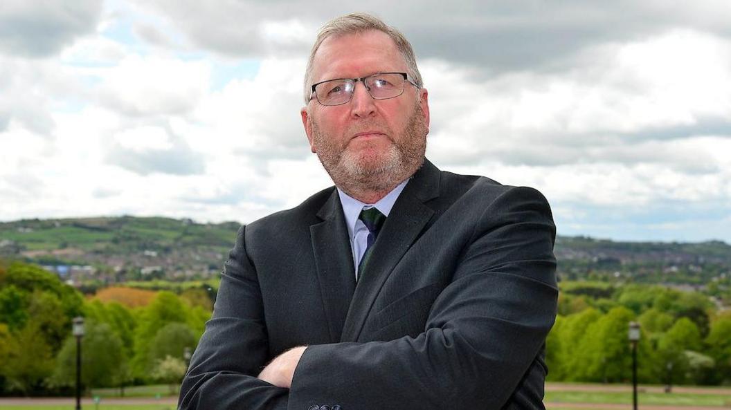 Doug Beattie standing with arms folded outside Stormont