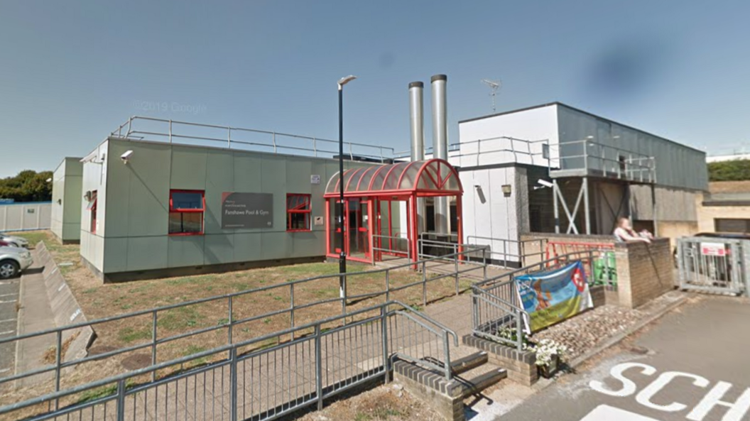 The entrance to Fanshawe Pool and Gym in Ware. A cladded building with a red glass-panelled awning over the entrance. 