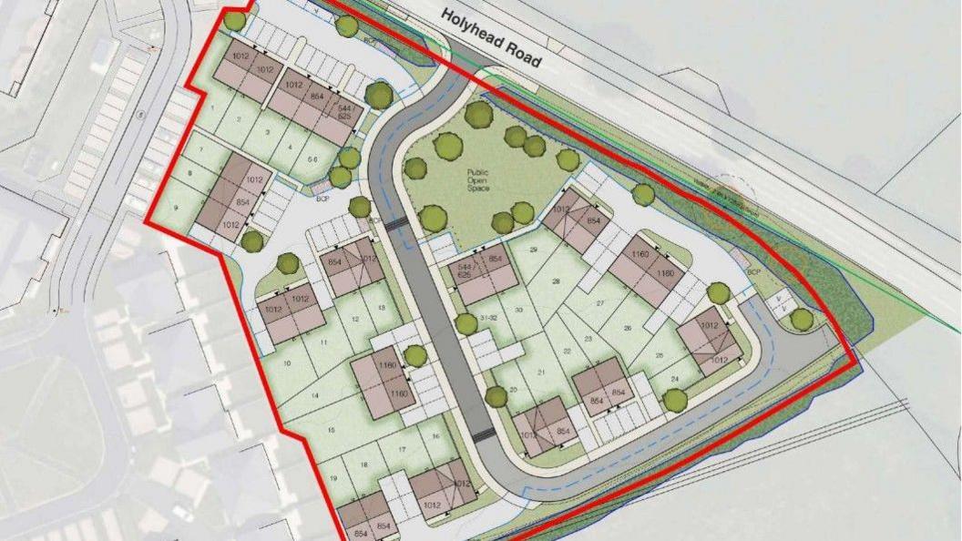 An aerial illustration of a proposed housing development with a red line around it. There are 32 brown squares representing houses, with white rectangles to show parking spaces. There are green spaces and trees illustrated