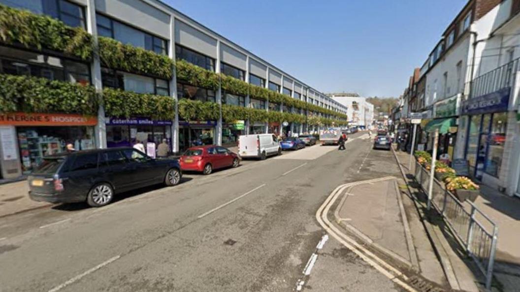 A street lined with shops and cars parked along it.