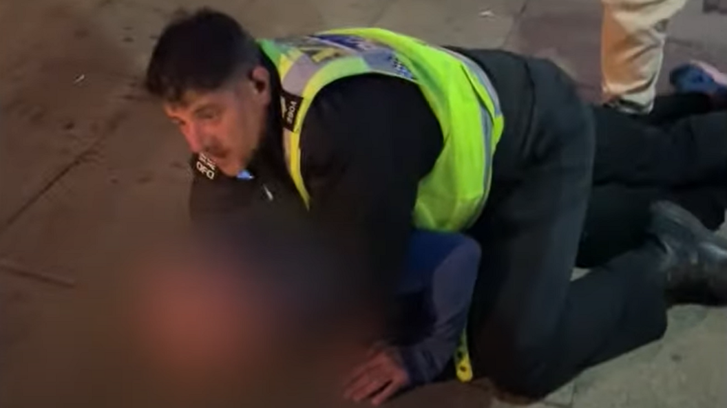 Man being restrained by police officer