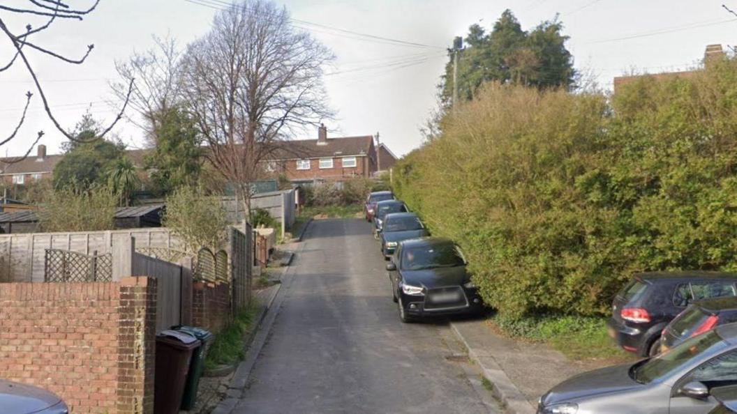 A row of vehicles are parked on a sloped curb at Southmount, Hollingdean.