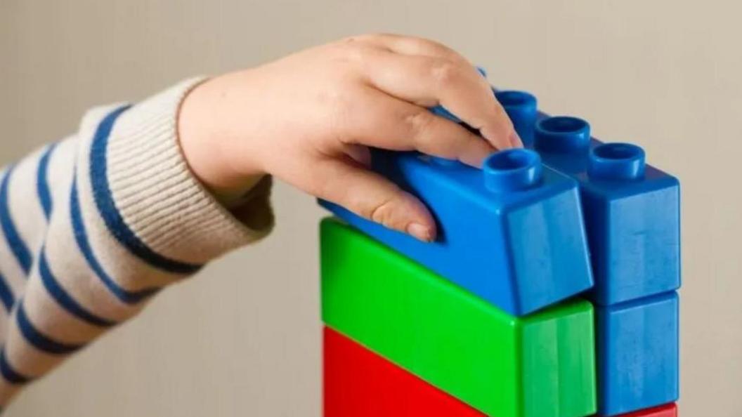 Hand of a child playing with building blocks