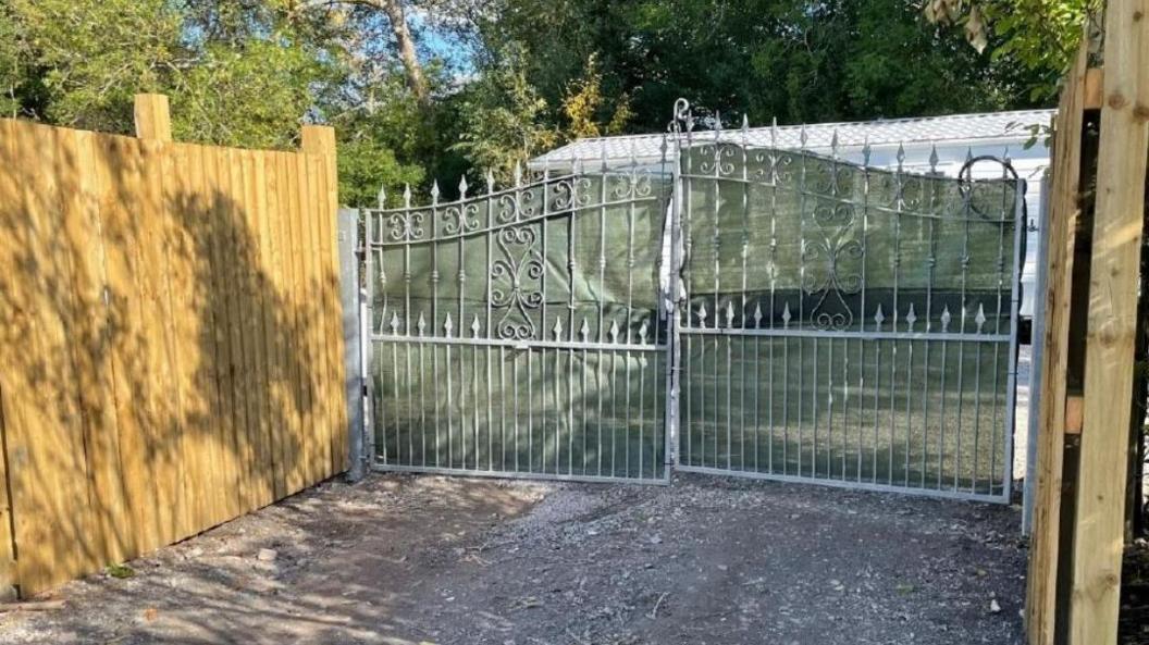 A mobile home behind gates and fences