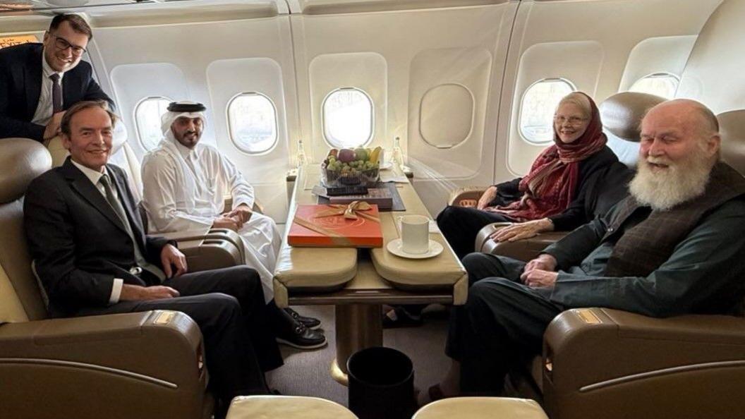 Barbie and Peter Reynolds sitting on a Qatari plane with diplomats 