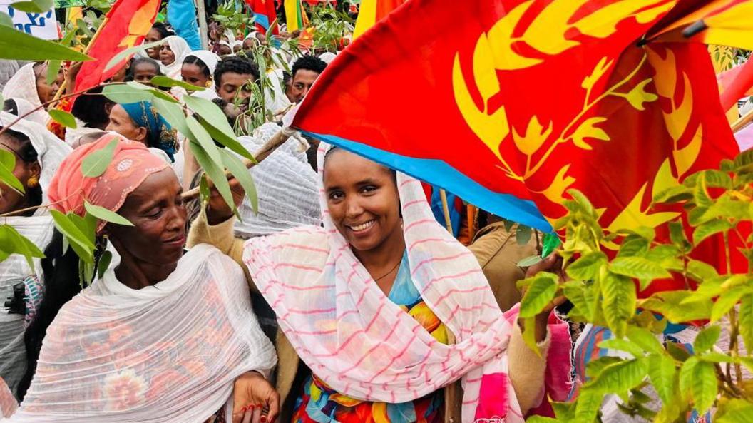 Two women smiling and waving the Eritrean flag