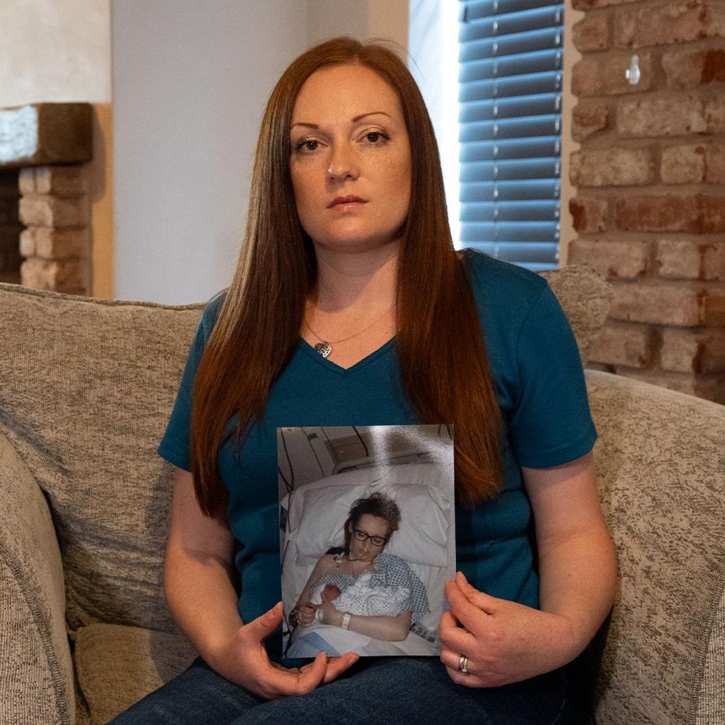 Felicity Benyon sits in an armchair holding a picture.