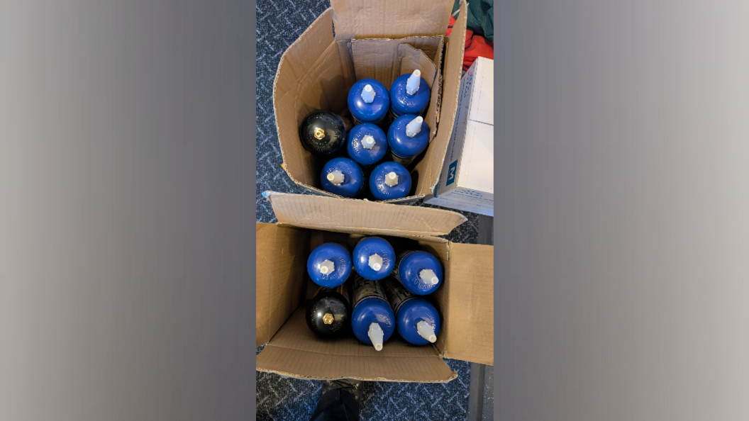 Two cardboard boxes containing blue canisters with metal tops.