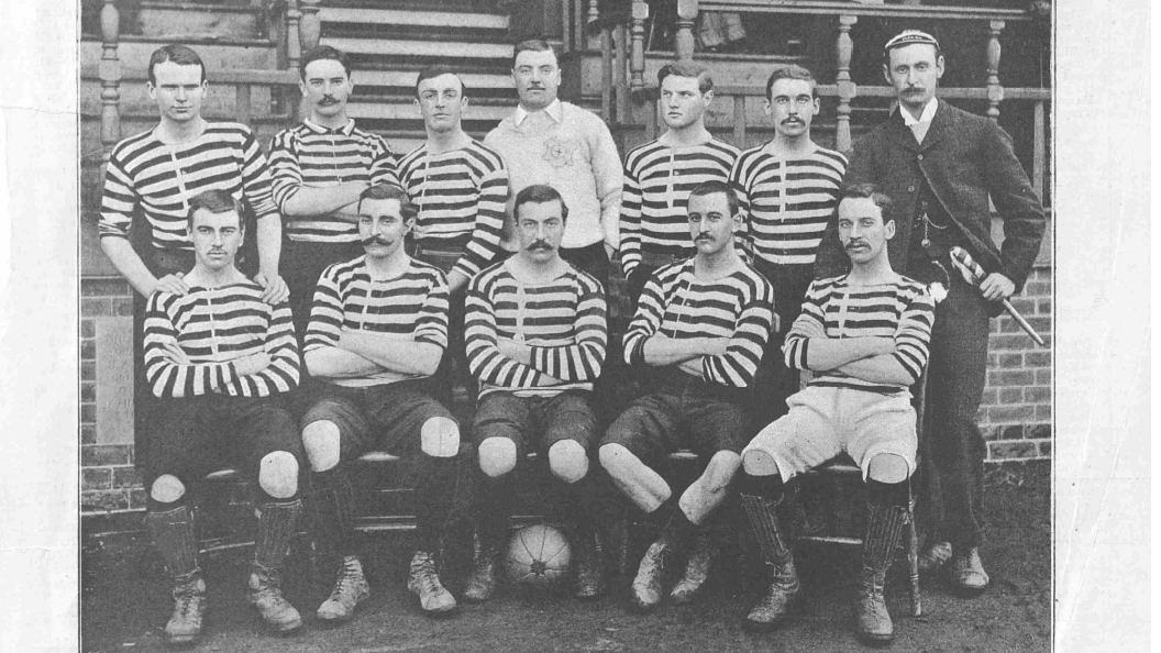 Sgioba London Caledonians ann an 1891. Tha Mac a' Phì na shuidhe san dàrna àite bhon làimh dheis. Dealbh bho Bhòrd Leabharlainn Bhreatainn. Còraichean uile glèidhte. Le taing do Thasglann Phàipearan-Naidheachd Bhreatainn