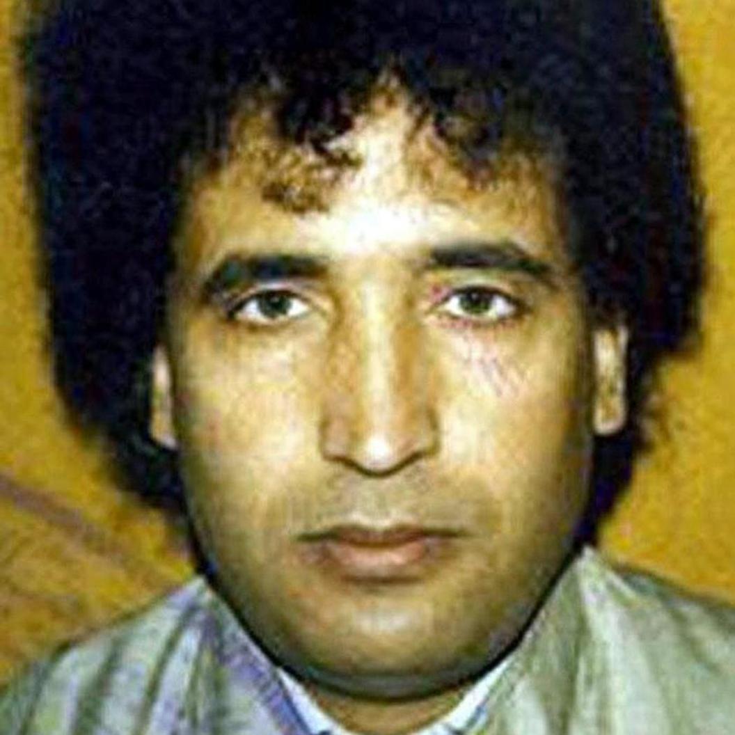 Abdulbasset Al Megrahi looking straight at the camera. He has black curly hair and there is a yellow background.