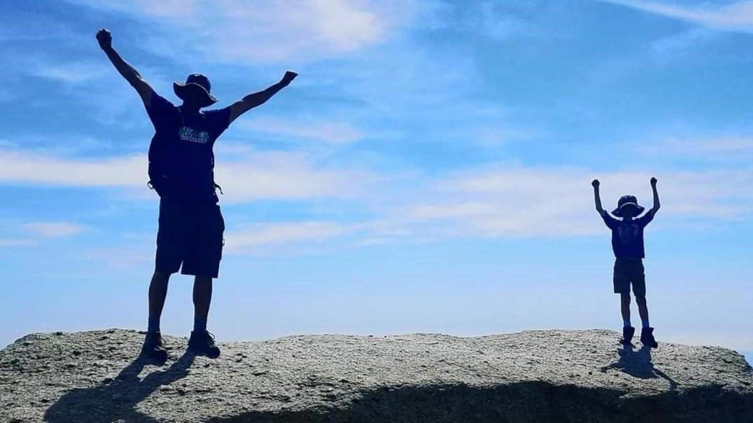 A silhouette of a man and a boy standing on a mountain