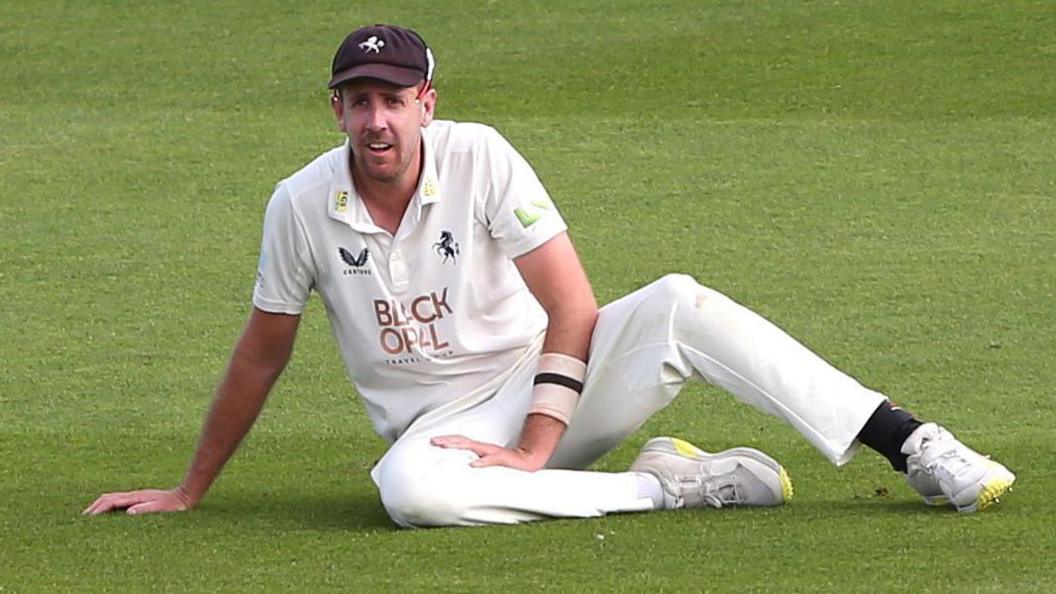 Kent pace bowler Matt Quinn sitting on the outfield during a County Championship game.