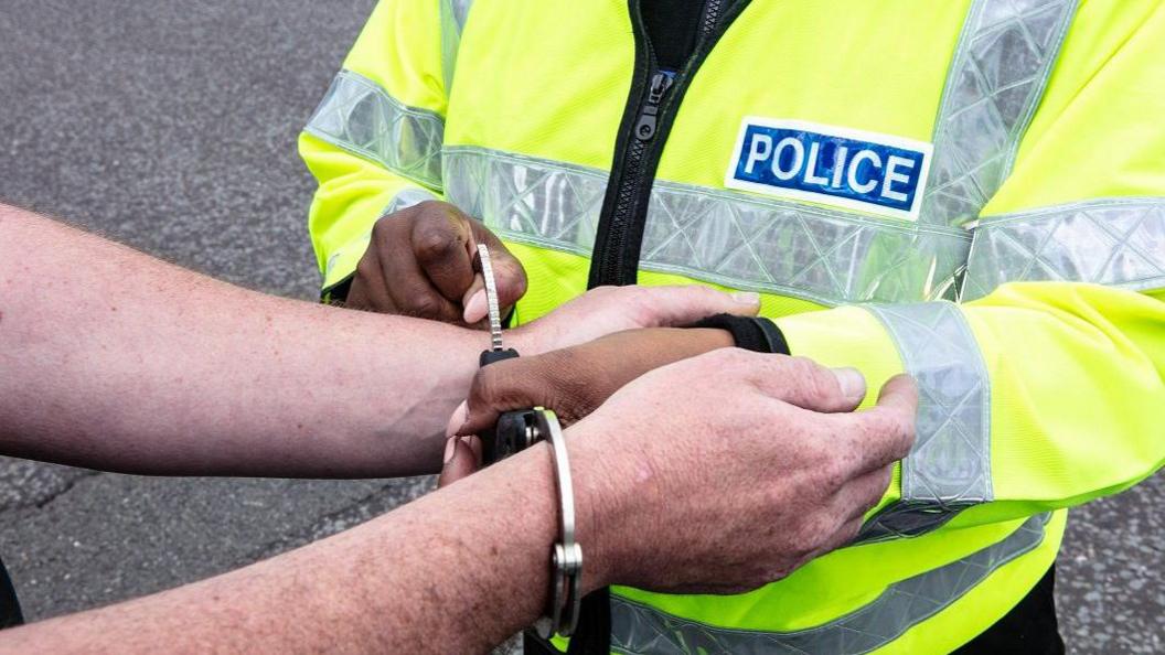 A man's hands being handcuffed by a female police officer. Only their hands can been seen.