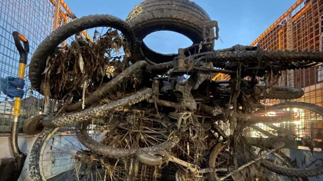 Bikes and rubbish loaded onto the back of a van after being extracted from the river