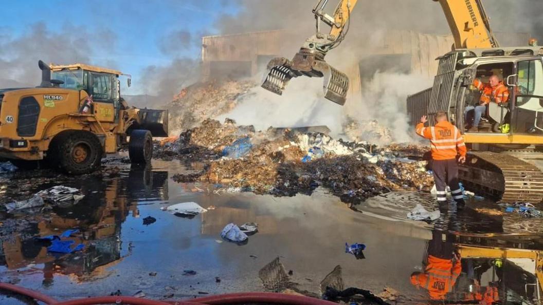 Workers trying to put out the fire at a large recycling centre