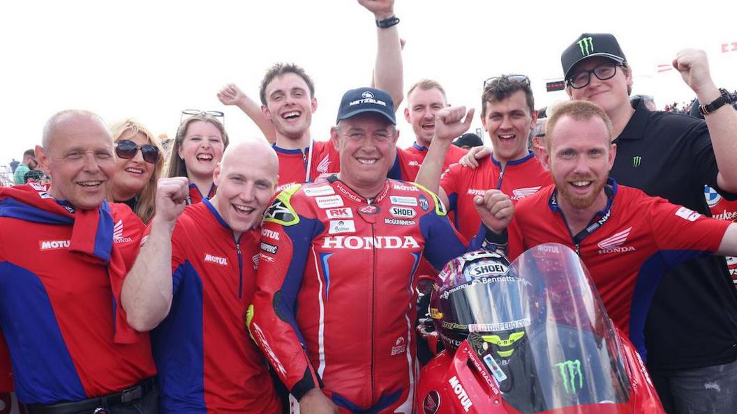 John McGuinness celebrates his 2024 NW200 Superstock team with team members and family