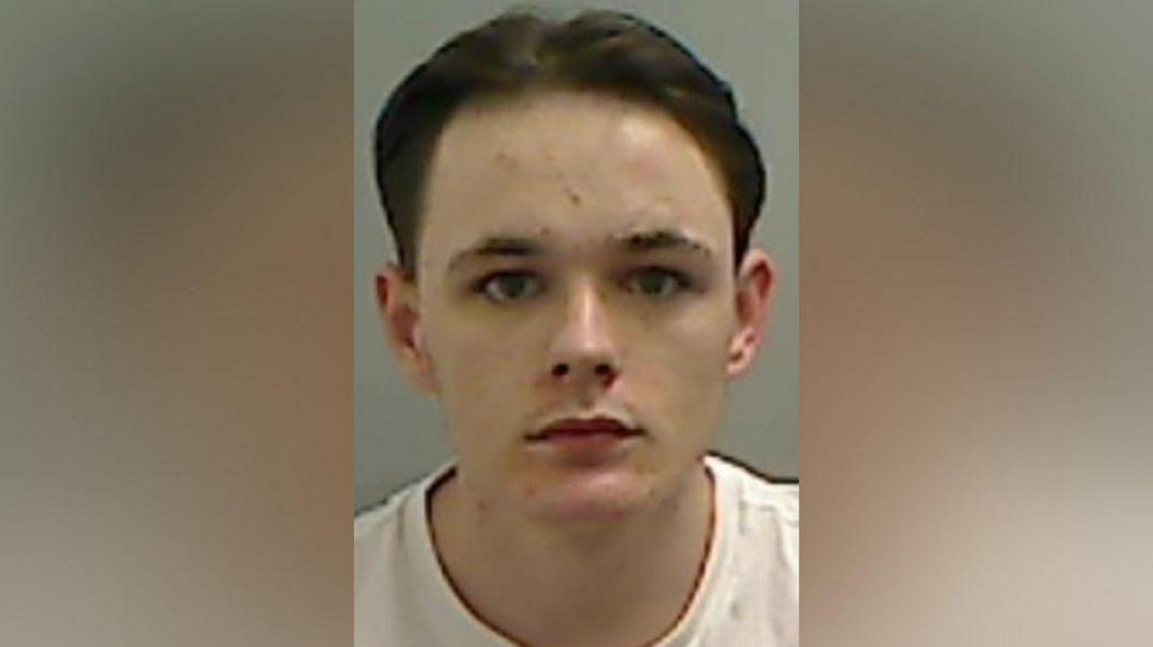 Mugshot of Finn-Gibbs. He is clean shaven with a spotty face and brown hair swept back.