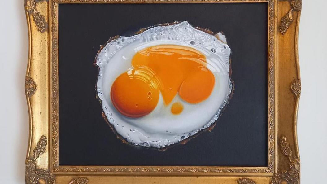 A framed picture of a double yolker on black canvas.