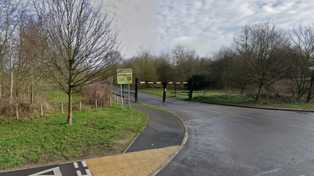 The entrance to Swadlincote Woodlands, with trees either side of an unassuming gate for cars to use