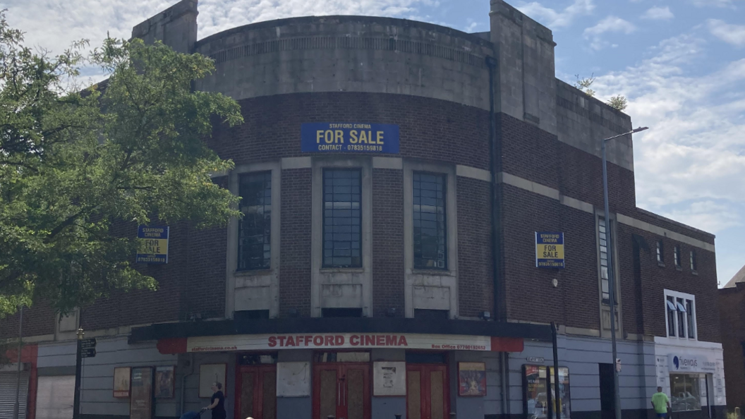 A curved red brick building with signs saying Stafford Cinema and For Sale