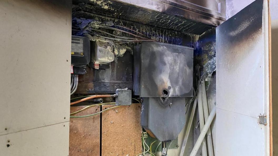 A fire in an electrical installation. There are wires, casing and fire damaged equipment, that has been kept in a box. 