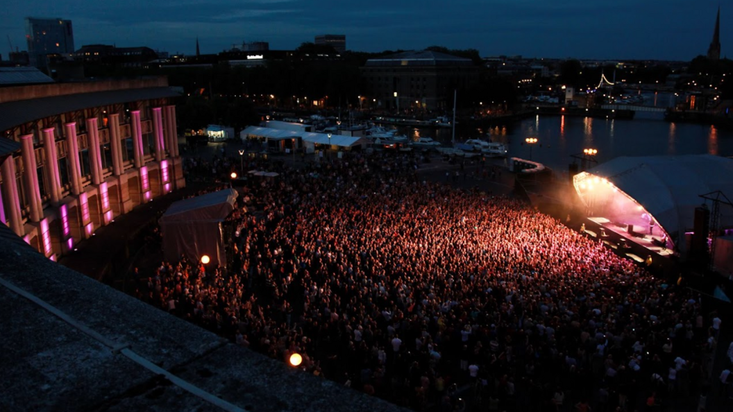 A night time shot of the amphitheatre with the main stage and thousands of fans in attendance