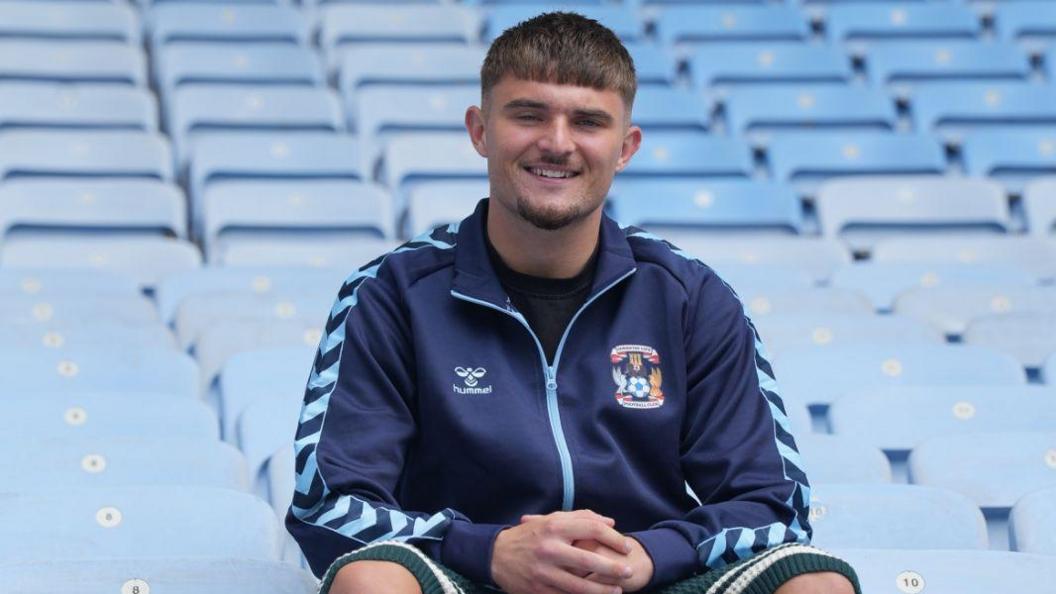 A smiling Callum Perry poses in the stands at Coventry Building Society Arena