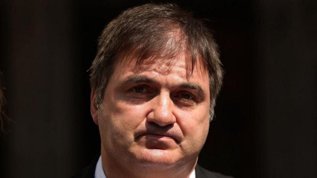 Barry George has dark hair and a white collared shirt