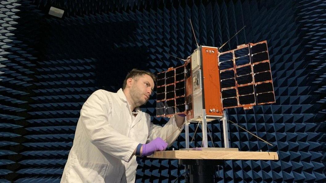 Man in lab coat looking at satellite 