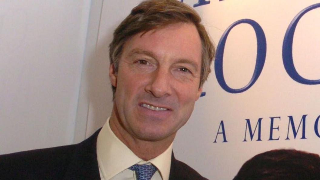 Lord Brockett during Lord Brockett Photocall at London Olympia in London, Great Britain. He wears a dark suit, white shirt and blue tie.