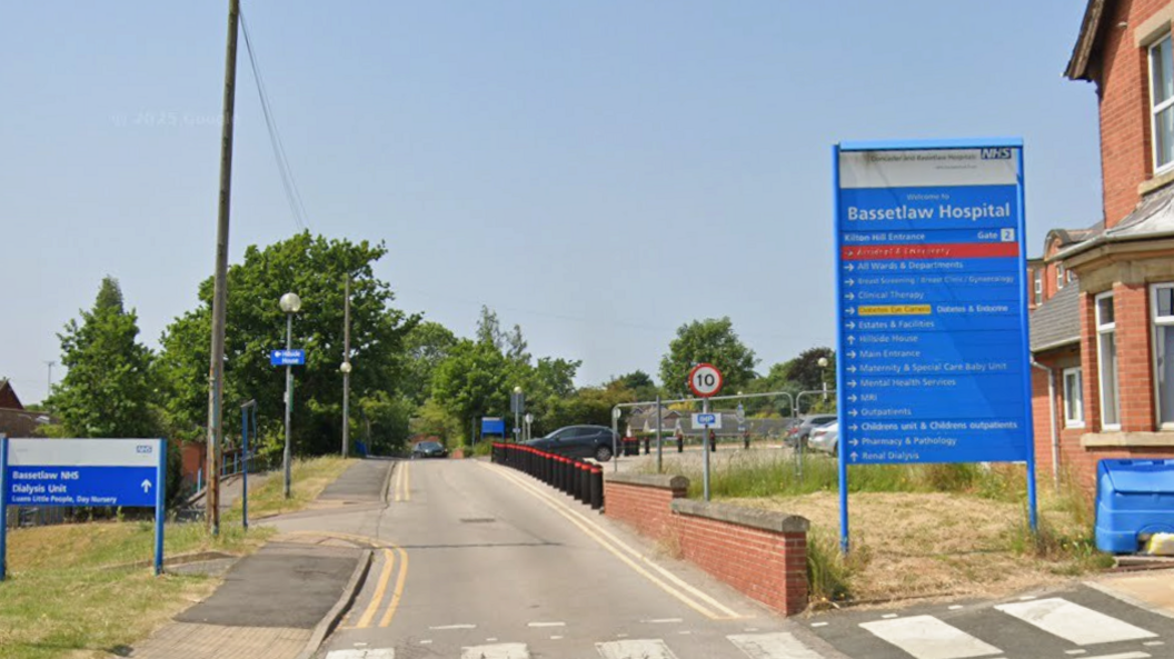 Blue sign which reads Bassetlaw Hospital with a 10mph sign in the background