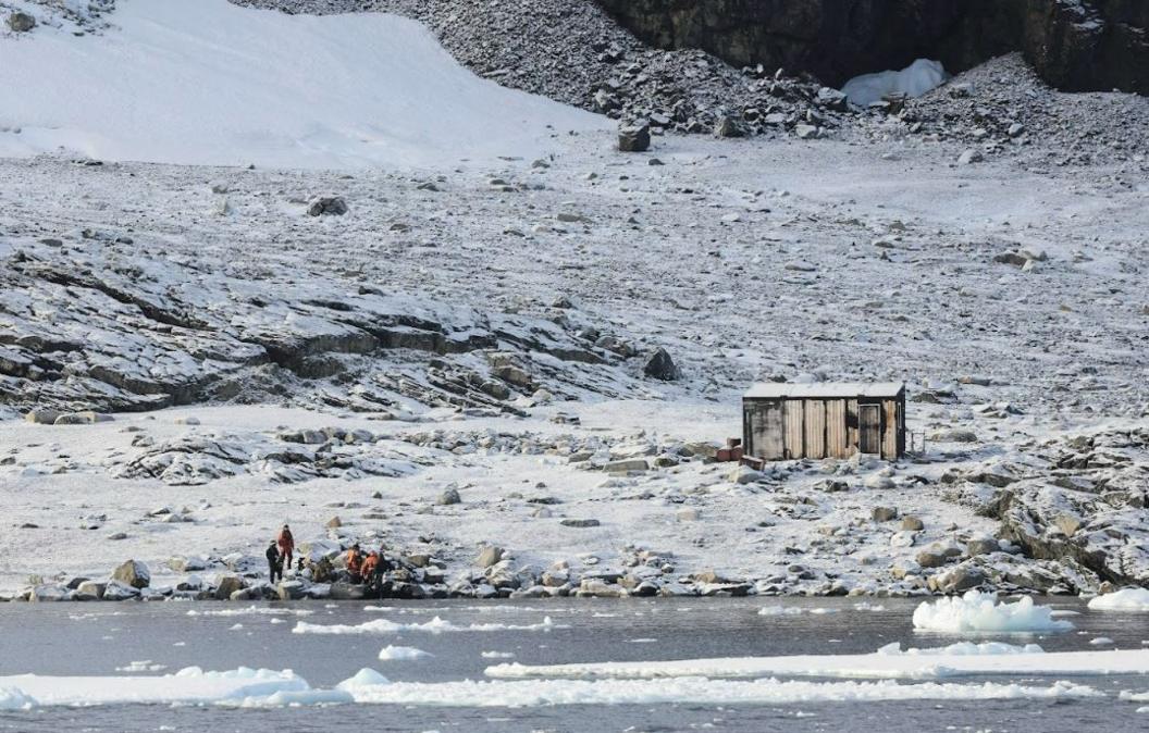 A small hut on Blaiklock Island in Antarctica, alone in a snowy and barren landscape. 