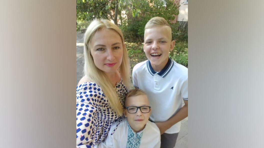 A woman smiles at the camera with her two sons