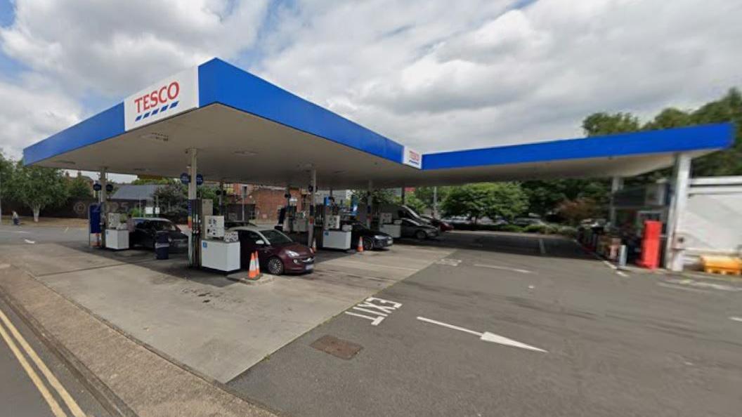 A Tesco petrol station forecourt, with three cars at three lines of pumps.