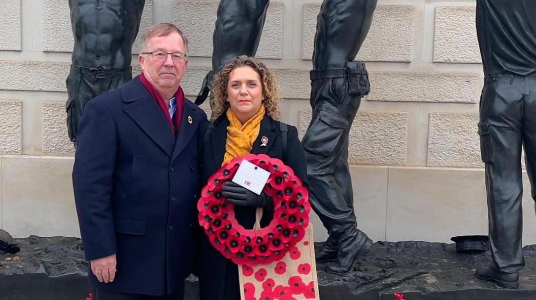 Hannah and Colin Ingram-Moore holding a poppy wreath at the National Arboretum