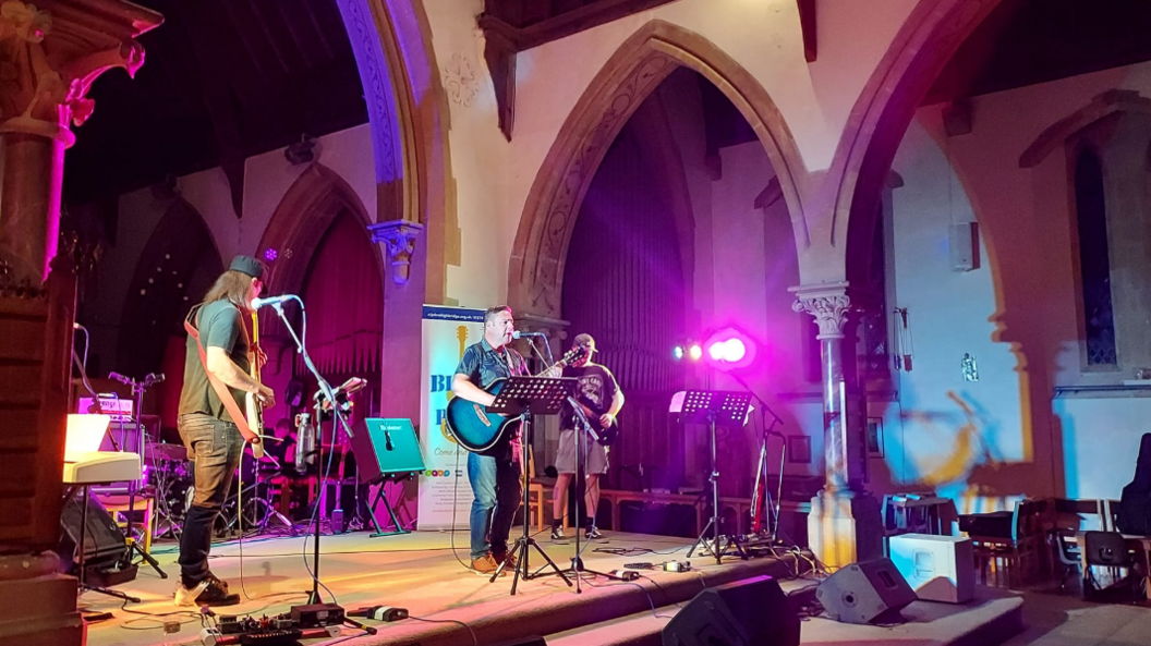 A blues band playing on stage in the nave of St John's church