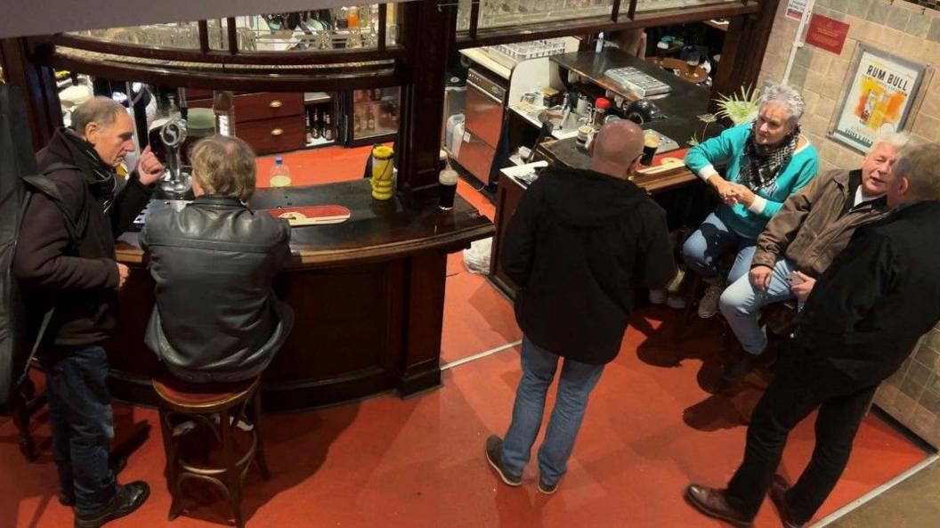 People drinking and talking in the main bar area.